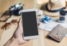 25 Essential Apps for Istanbul: Transport, Food, Money, and More Hand holding a smartphone with travel accessories like passport and camera, planning a trip with apps