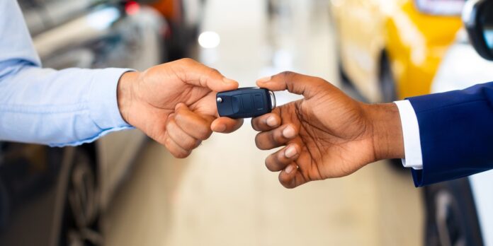 Customer receiving car keys from a rental agent in a dealership