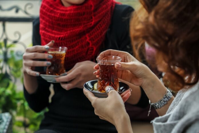 Two women sharing Turkish tea in traditional tulip-shaped armudu glasses