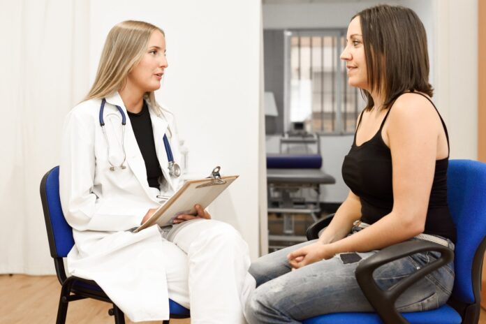 Doctor with a clipboard speaking with a patient in a consultation room